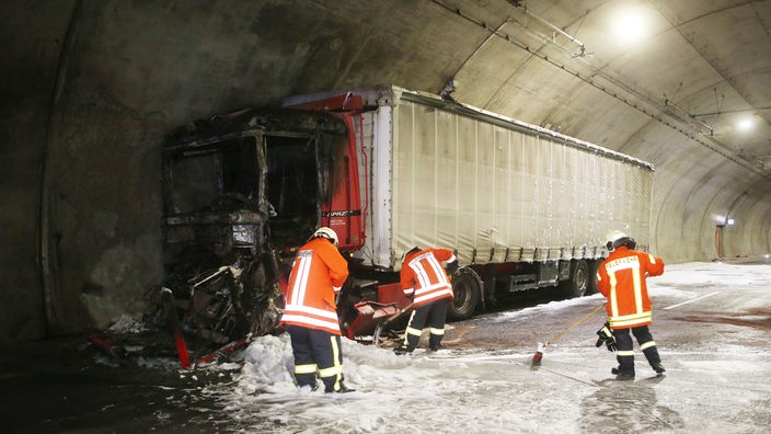 Feuerwherleute mit einem gelöschten LKW in einem Tunnel