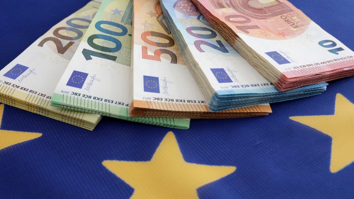 Euroscheine liegen auf einer Europaflagge.