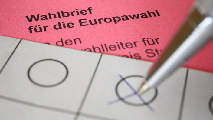 Eine Frau kreuzt einen Wahlzettel für die Briefwahl zum europäischen Parlament an