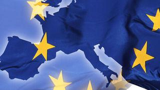Die Fahne der EU mit einer Landkarte von Europa im Hintergrund.
