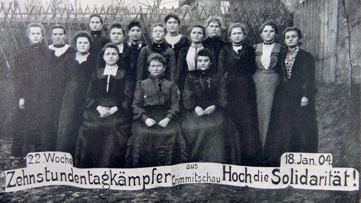 Gruppenfoto von streikenden Frauen, darunter der Text: "22. Woche. Zehnstundentagkämpfer aus Crimmitschau. Hoch die Solidarität! 18. Jan. 04"