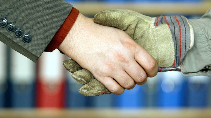 Zwei Hände schütteln sich, eine davon trägt einen Arbeiterhandschuh