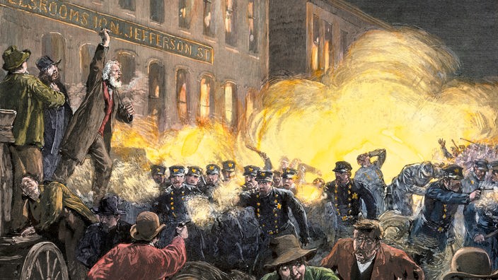 Ein Gemälde zeigt eine demonstrierende Menschmenge vor einem brennenden Feuer; ein Mensch schießt auf eine Gruppe von Polizisten