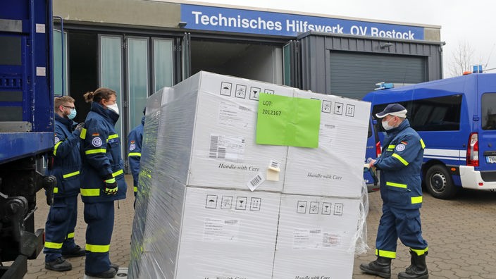 Mitarbeiter des Technischen Hilfswerks laden eine Palette Schnelltests von einem LKW