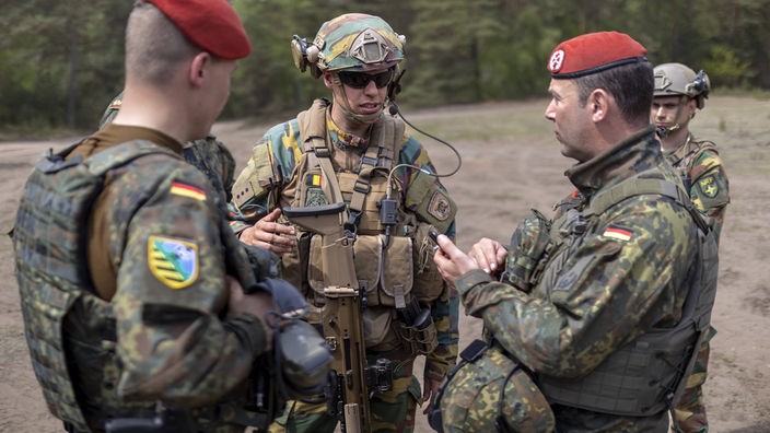 Deutsche und belgische Soldaten der so genannten schnellen Eingreiftruppe der Nato während der Übung 'Wettiner Heide' im Gespräch.