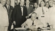 Schwarzweißfoto: US-Präsident Harry Truman unterzeichnet den Nordatlantikpakt am 4. April 1949.