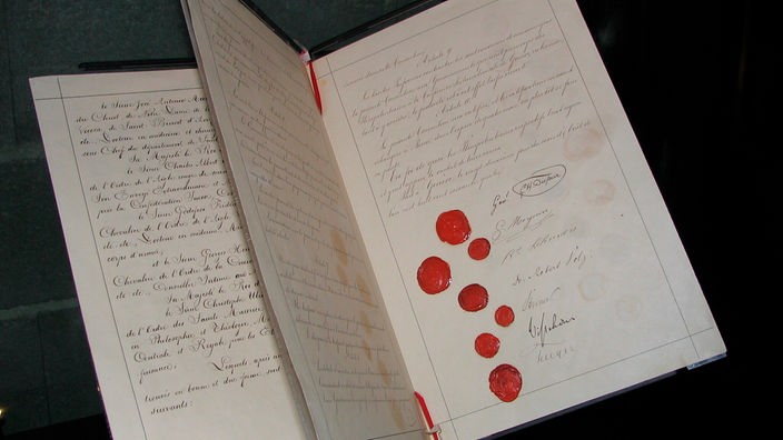 Die drei Fotos zeigen die Originalurkunde der ersten Genfer Konvention mit den Siegeln und Unterschriften der Länder-Delegierten.