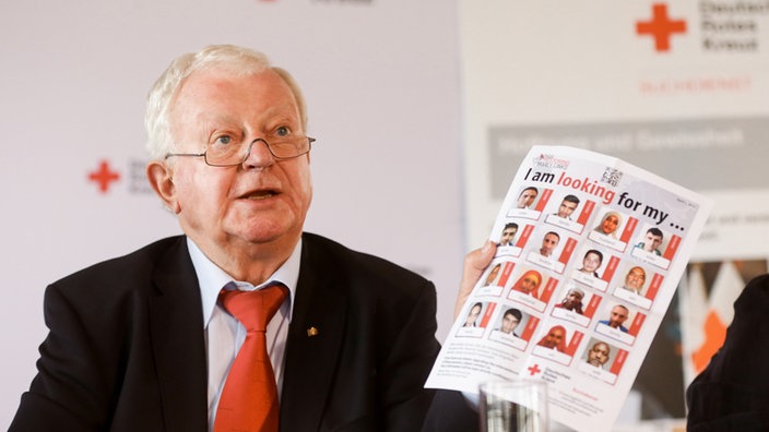 DRK-Präsident Rudolf Seiters präsentiert am 04.05.2015 in Hamburg auf einer Pressekonferenz zur Gründung des DRK-Suchdienstes vor 70 Jahren ein aktuelles Plakat, das für die Online-Suche wirbt | Bildquelle: WDR / dpa/Ulrich Perrey DRK-Präsident Rudolf Seiters präsentiert am 04.05.2015 in Hamburg auf einer Pressekonferenz zur Gründung des DRK-Suchdienstes vor 70 Jahren ein aktuelles Plakat, das für die Online-Suche wirbt
