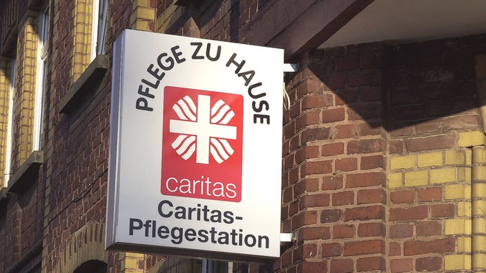 Schild an der Hauswand einer Pflegestation der Caritas in Much.