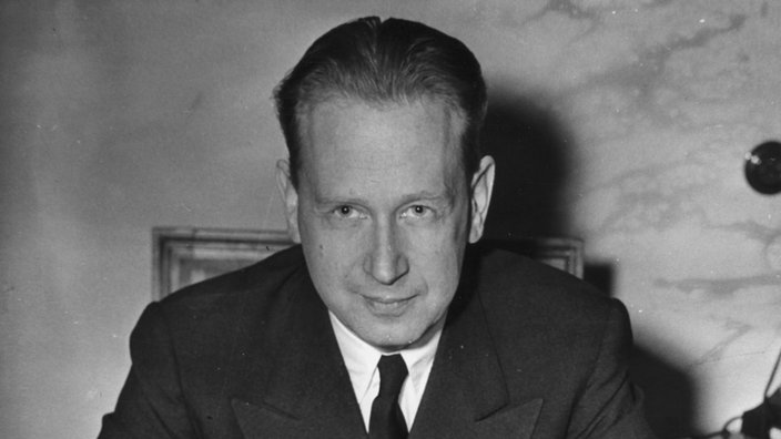 Dag Hammarskjöld sitzt an einem Schreibtisch und schaut in die Kamera. | Bildquelle: akg-images/ARC Dag Hammarskjöld sitzt an einem Schreibtisch und schaut in die Kamera.