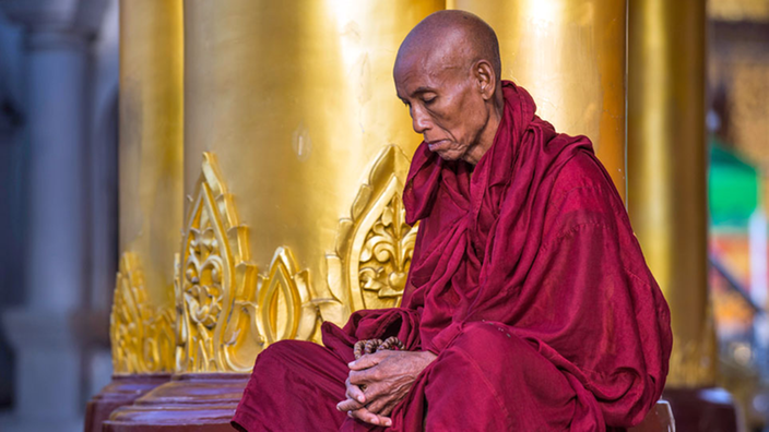 Ein buddhistischer Mönch sitzt auf dem Boden.