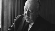 Das Porträt-Foto zeigt Alfred Hitchcock in fortgeschrittenem Alter im schwarzen Anzug und Krawatte