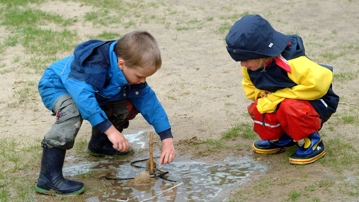 Geschwisterpaar spielt im Matsch.