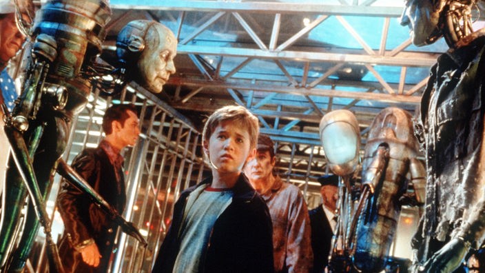 Roboterjunge David aus dem Film "A.I. – Künstliche Intelligenz", umgeben von Robotern.