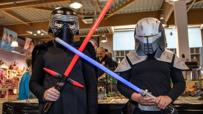 Zwei Star-Wars-Fans in Kostümen kämpfen mit Plastik-Laserschwertern.