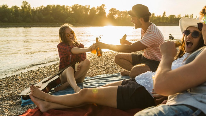 Vier Freunde sitzen entspannt am See