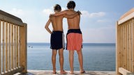 Zwei Jungs stehen Arm in Arm auf einem Steg.