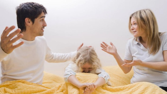 Ehepaar streitet im Bett, Kind sitzt hilflos dazwischen. | Bildquelle: imago/blickwinkel Ehepaar streitet im Bett, Kind sitzt hilflos dazwischen.