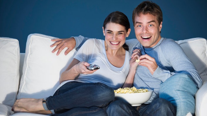 Ein Pärchen sitzt auf einem Sofa, isst Popcorn und schaut fern. | Bildquelle: Agentur:ddp images Ein Pärchen sitzt auf einem Sofa, isst Popcorn und schaut fern.