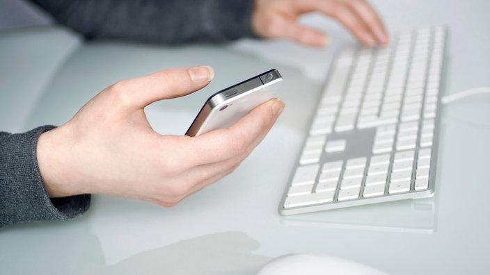 Eine Person sitzt am Computer und hält gleichzeitig das Handy in der Hand. | Bildquelle: Annika Fußwinkel / WDR Eine Person sitzt am Computer und hält gleichzeitig das Handy in der Hand.
