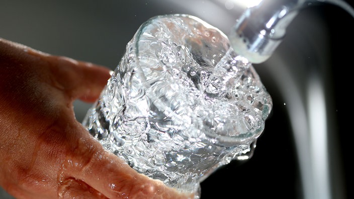 Jemand füllt Wasser in ein Glas, das überläuft. | Bildquelle: WDR/dpa Jemand füllt Wasser in ein Glas, das überläuft.