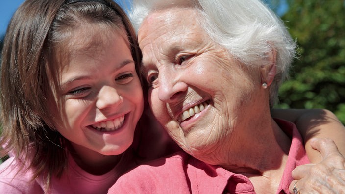 Eine Großmutter und ihre Enkelin lächeln.