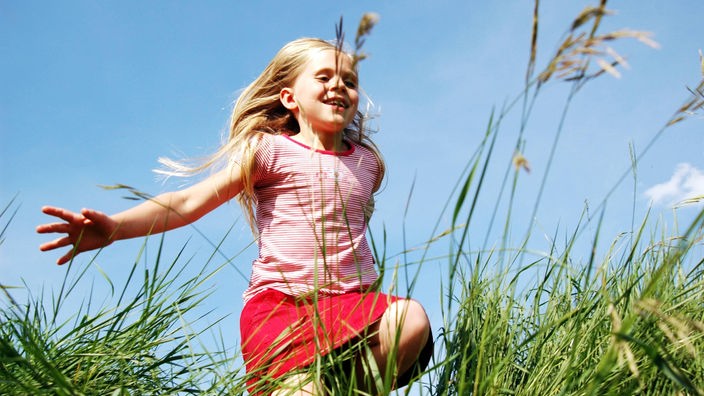 Ein Mädchen läuft über eine Sommerwiese.