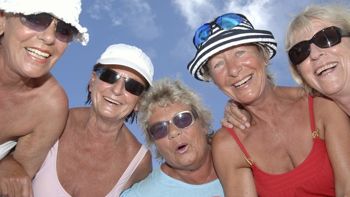Gruppe von lachenden Senioren am Strand.