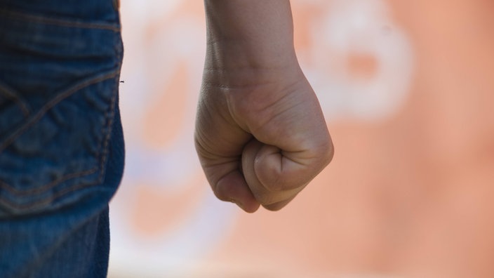 Junge steht mit geballter Faust vor einer Graffitiwand | Bildquelle: imago/emil umdorf Junge steht mit geballter Faust vor einer Graffitiwand