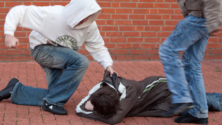 SYMBOLBILD - Jugendlicher schlägt auf einen anderen am Boden liegenden Jugendlichen ein, ein zweiter tritt zu