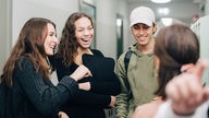 Vier Jugendliche unterhalten sich lachend im Schulflur