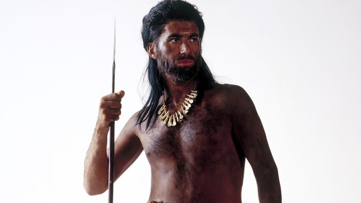 Nachbildung eines dunkelhäutigen Steinzeitmenschen mit einem Fell um die Lenden und einem Speer