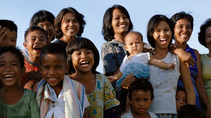 Eine Gruppe asiatischer Frauen und Kinder lacht fröhlich in die Kamera