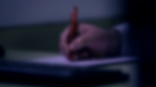 Unscharfes Bild, menschliche Hand schreibt etwas auf.