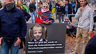 Querdenker-Demonstranten mit einem Plakat auf dem ein Mädchen abgebildet ist.
