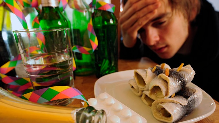 Ein junger Mann schaut auf beliebte Anti-Kater-Mittel: Rollmops und Kopfschmerztabletten | Bildquelle: ddp/Philipp Guelland Ein junger Mann schaut auf beliebte Anti-Kater-Mittel: Rollmops und Kopfschmerztabletten