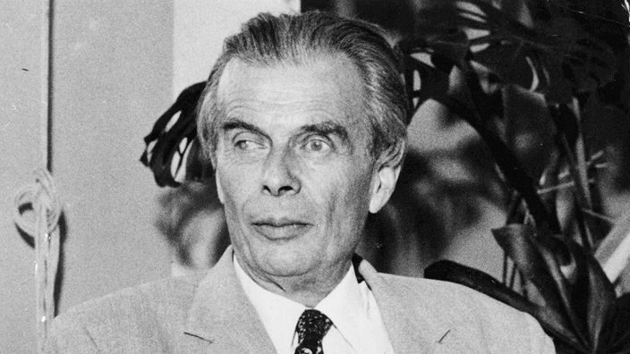 Schwarzweiß-Foto von Aldous Huxley, der in einem Lehnstuhl sitzt.