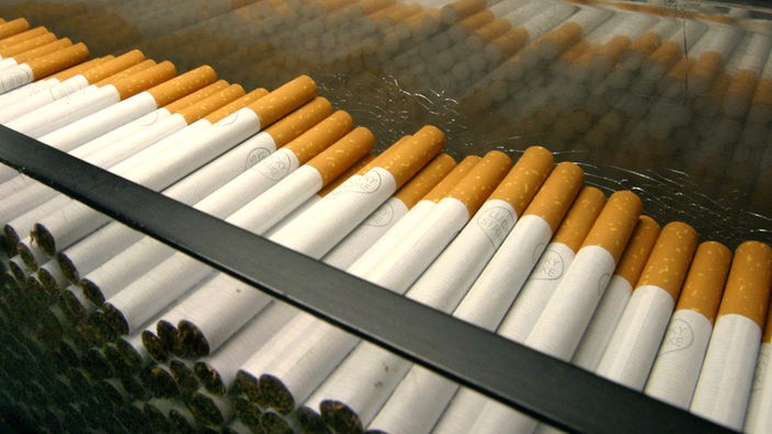 Einige Dutzend Zigaretten liegen auf einem Fließband.