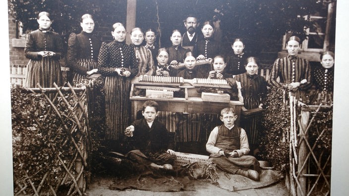Schwarzweiß-Foto: Männer, Frauen und Kinder mit Zigarren.