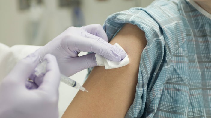Ein Arzt gibt einem Kind eine Impfung per Spritze in den Oberarm.