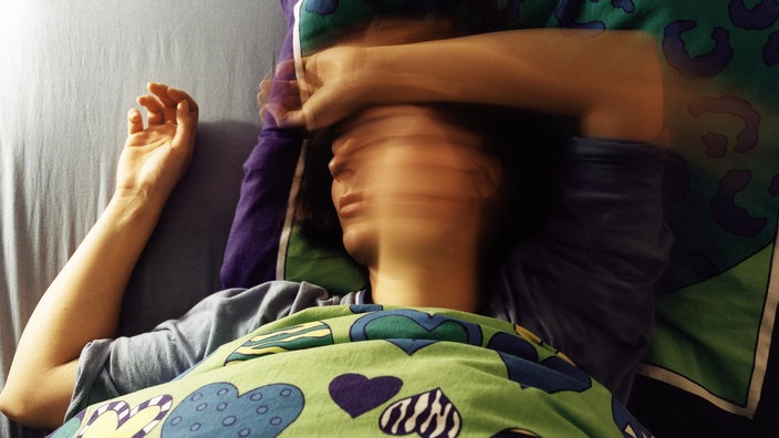 Eine Frau dreht sich im Bett hin und her | Bildquelle: Stephan Elleringmann/laif Eine Frau dreht sich im Bett hin und her