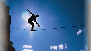Ein Mann balanciert auf einem Seil in der Luft.