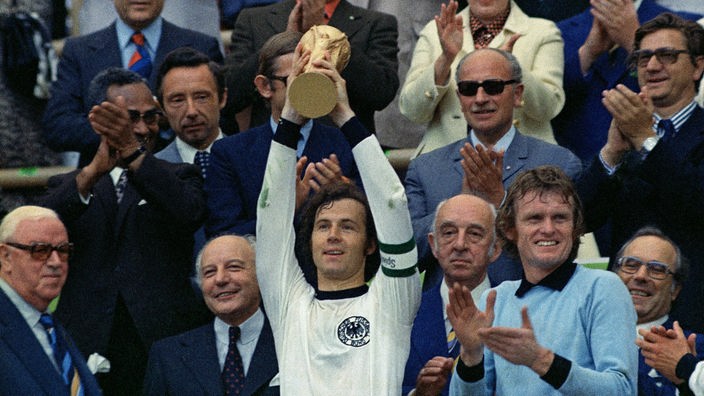 Der deutsche Kapitän Franz Beckenbauer hält mit beiden Händen den goldenen Weltpokal