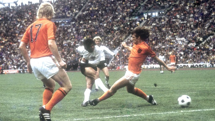 Gerd Müller schießt aus der Drehung aufs Tor der Niederländer. Ein niederländischer Spieler grätscht am Ball vorbei.