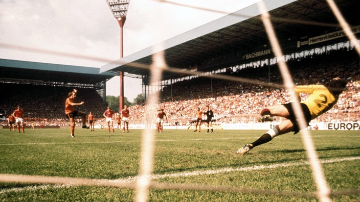 Spielsituation von hinten: Ein holländischer Spieler schießt gerade einen Elfmeter in die linke Ecke des Tores. | Bildquelle: Imago Spielsituation von hinten: Ein holländischer Spieler schießt gerade einen Elfmeter in die linke Ecke des Tores.