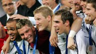 Seitliche Aufnahme: Die deutschen Spieler Odonkor, Podolski, Schweinsteiger und Lahm liegen sich in den Armen, lachen und haben Medaillen um den Hals gehängt.