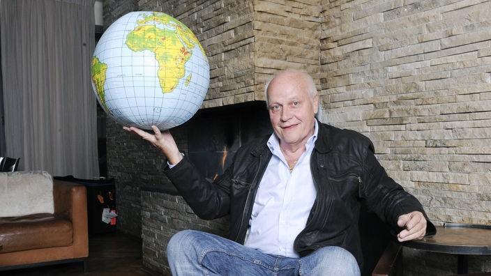 Otto Pfister auf einem Stuhl mit einem Globus in der Hand