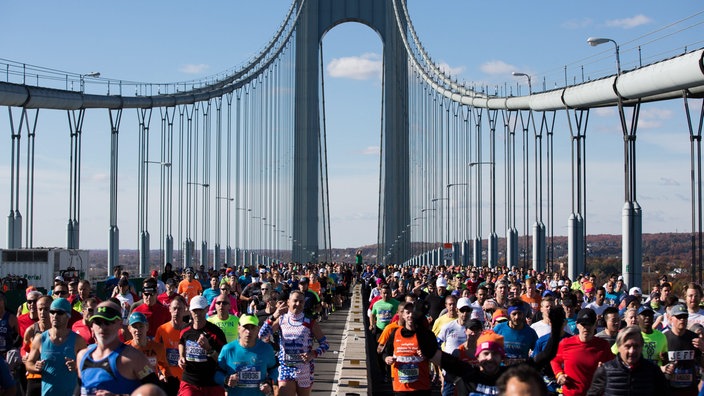 Hunderte Menschen joggen über eine Brücke in New York. | Bildquelle: dpa/Alba Vigaray Hunderte Menschen joggen über eine Brücke in New York.