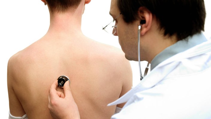 Ein Arzt hört den Rücken eines Patienten mit einem Stethoskop ab.