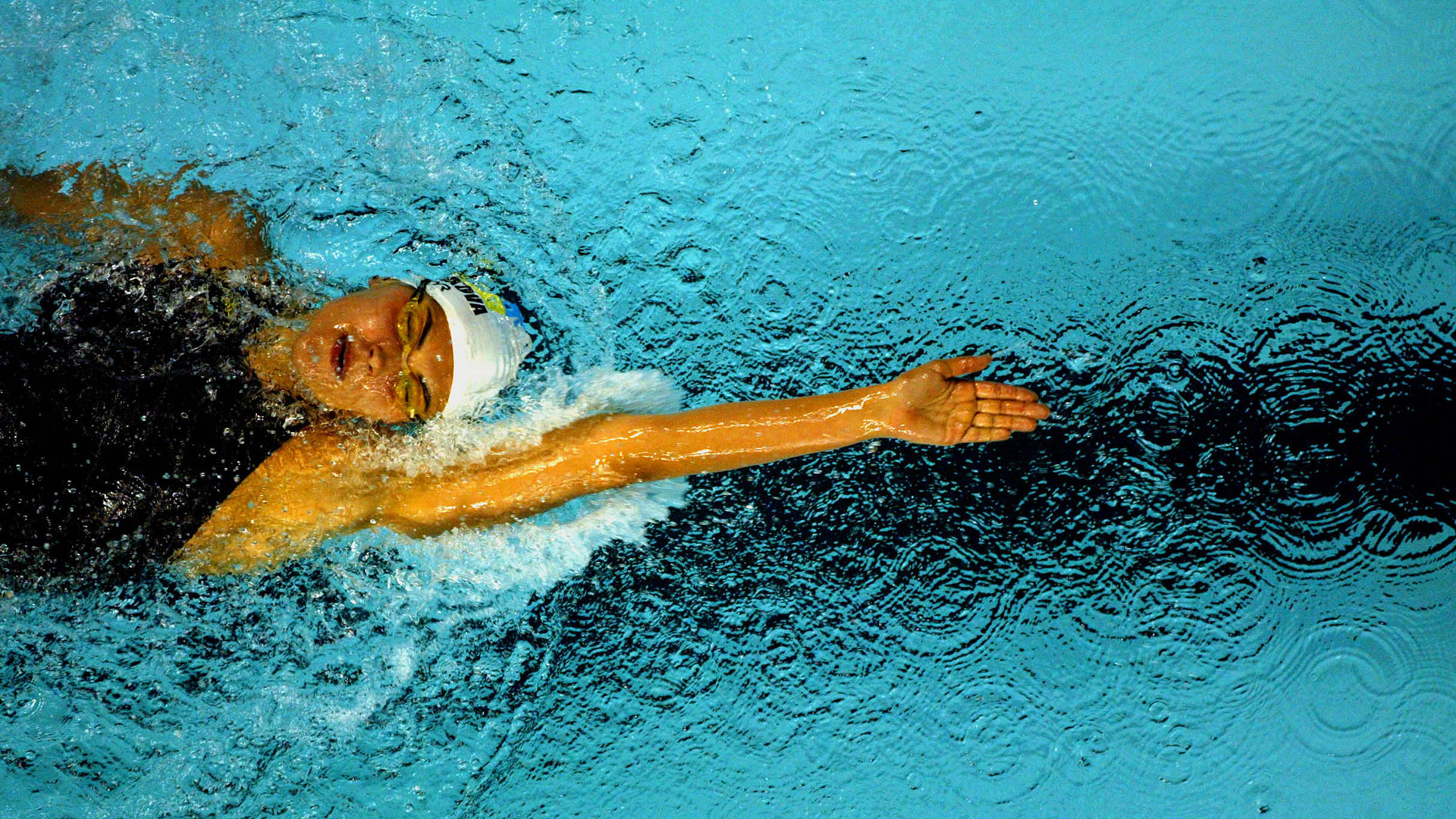 Schwimmerin mit schwarzem Badeanzug beim Rückenschwimmen